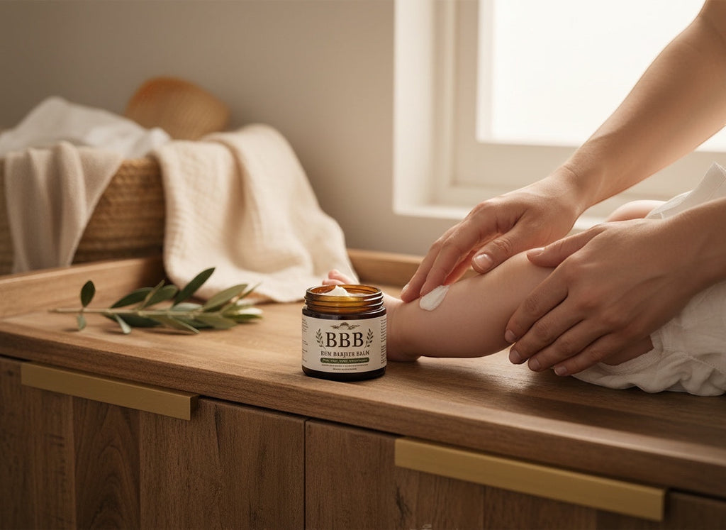 The Beef Bus Bum Barrier Balm in an amber jar being applied to a baby's leg on a wooden changing table.