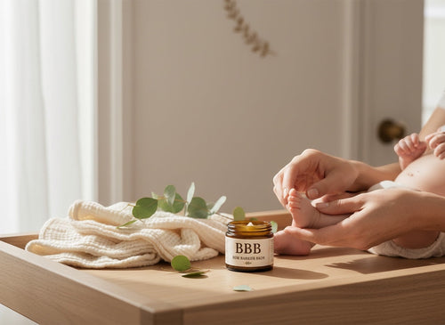 The Beef Bus Bum Barrier Balm in an amber glass jar on a changing table with a baby's feet and natural muslin cloth.